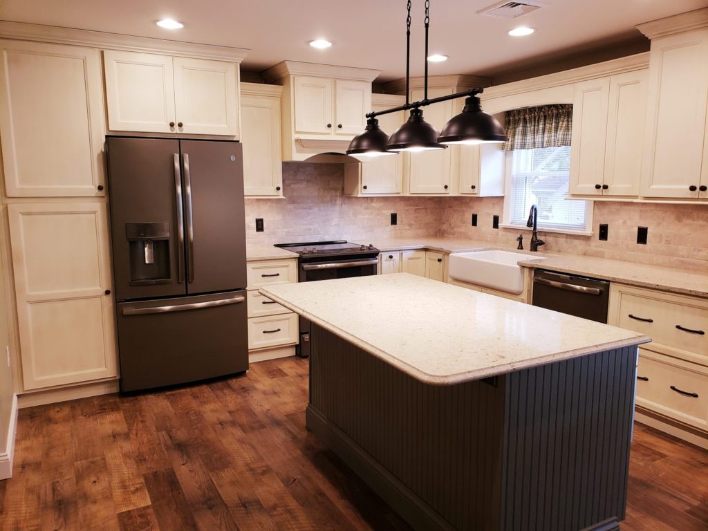 Newly renovated kitchen with white cabinets, marble countertops, and gray kitchen island