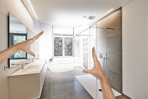 A pair of male hands outlining a bathroom in which the middle is hand-drawn to show the potential renovation ideas