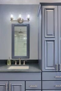 A newly installed bathroom vanity with spacious cabinets and blue mirror
